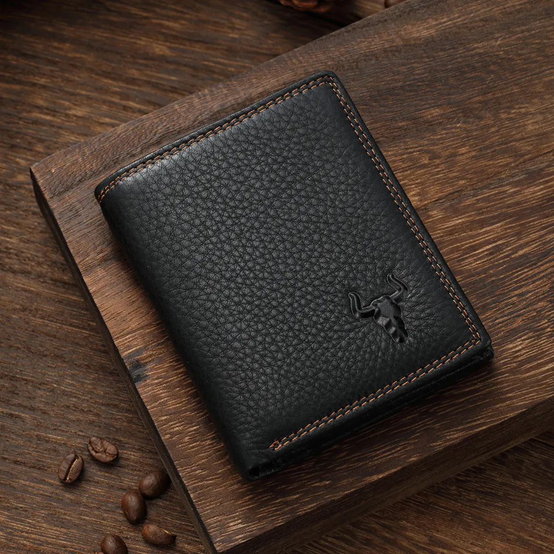 MING CLAN black pebble-grain leather bifold wallet lying flat on a wooden surface, showcasing vintage contrast stitching.