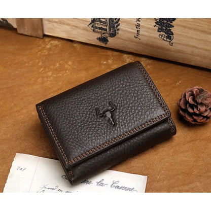 MING CLAN men's coffee vintage leather trifold wallet, front view with embossed bull logo on a wooden desk.